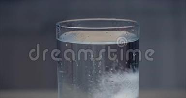 两片阿司匹林片落入一杯晶莹剔透的水中，气泡在一杯水中沸腾.. 健康观念。